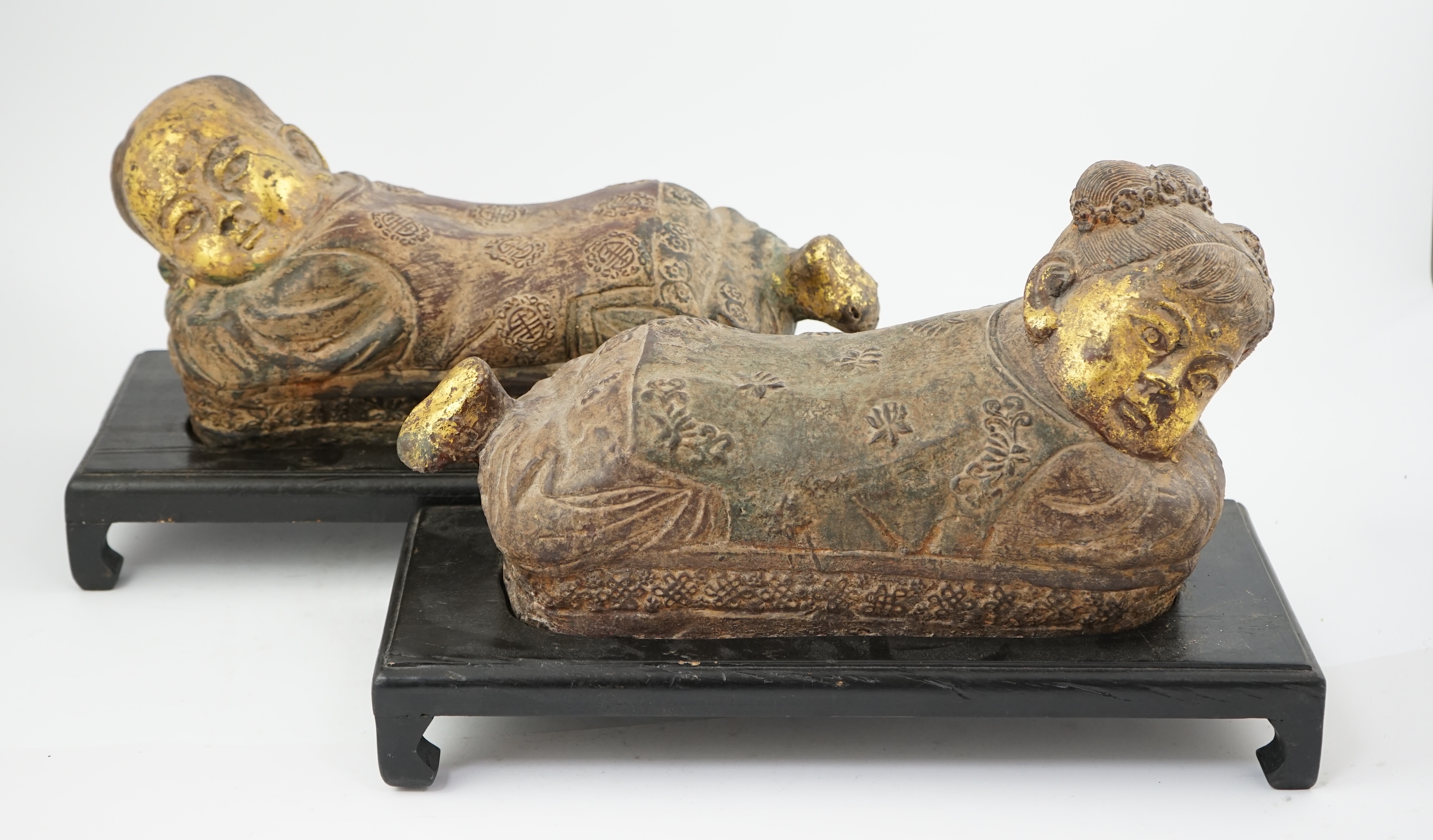 Two Chinese polychrome decorated iron pillows, modelled as sleeping children, on ebonised wood plinths, 44cm long. Condition - fair to good